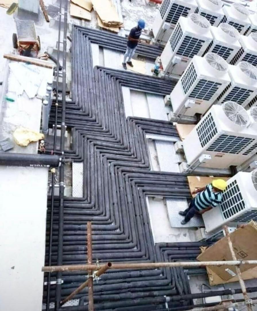 Carrier Air Conditioning technicians installing rooftop refrigerant piping on site